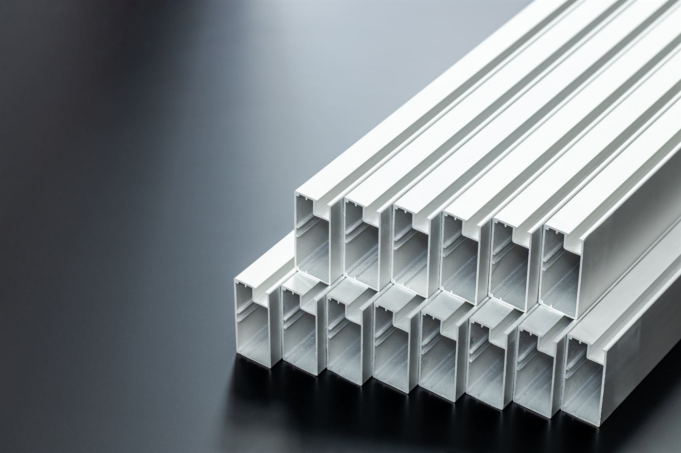 Stacked aluminium extrusion profiles on a dark background