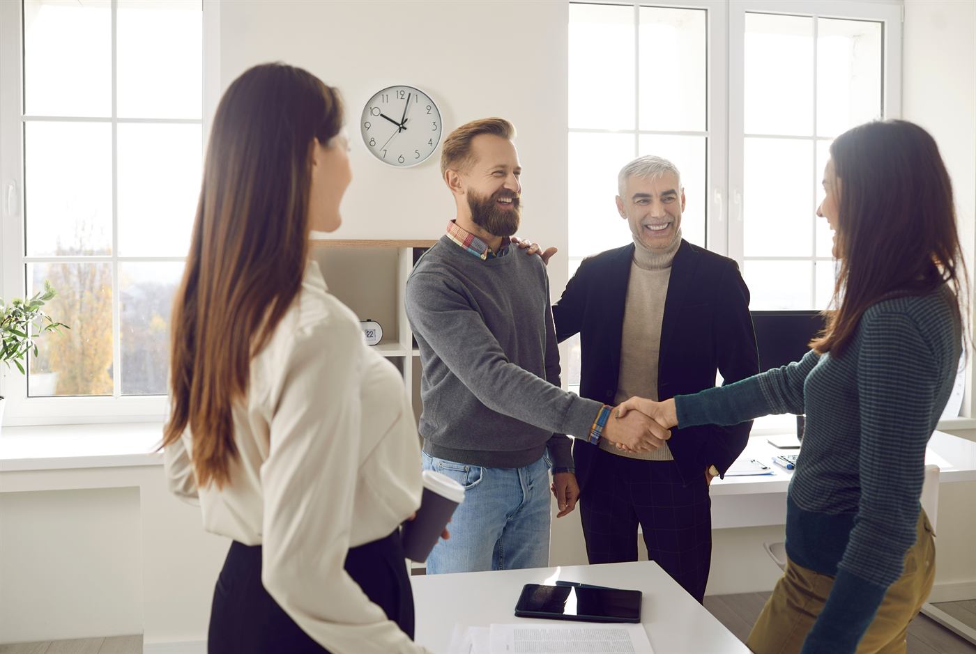 Account team welcoming a customer with a handshake in a bright office